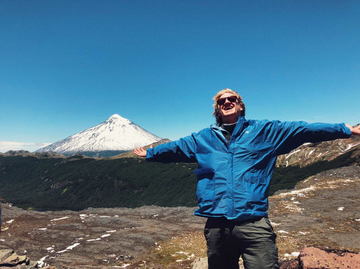 A person with their arms outstretched with a view of a mountain in the background.