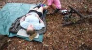 A woman laying on a blanket in the woods.