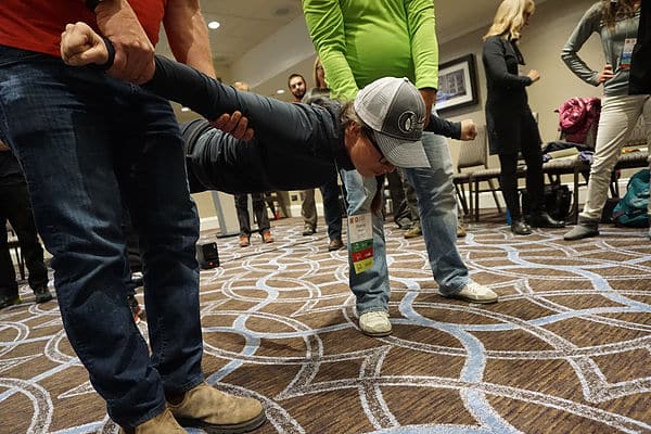 A group of people doing push ups in a conference room.