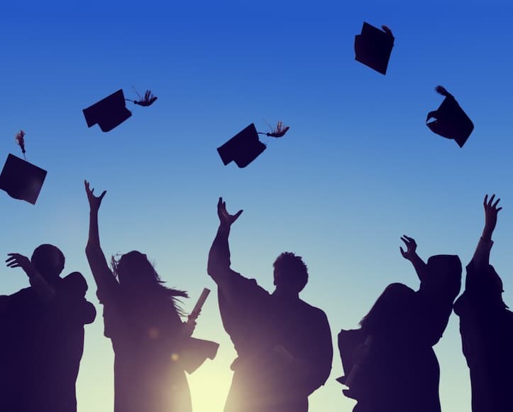 Silhouettes of graduates tossing their caps in the air.