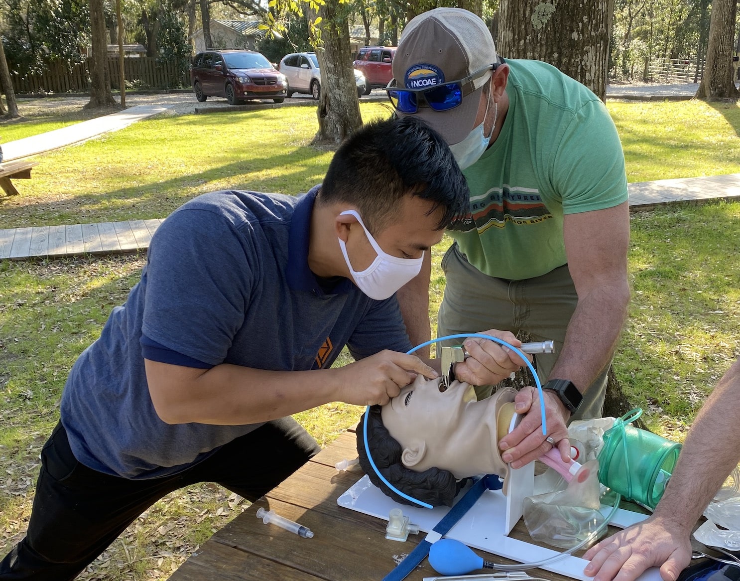 A group of people working on a mannequin in a park.