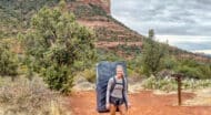 A woman carrying a backpack on a dirt trail in sedona, arizona.