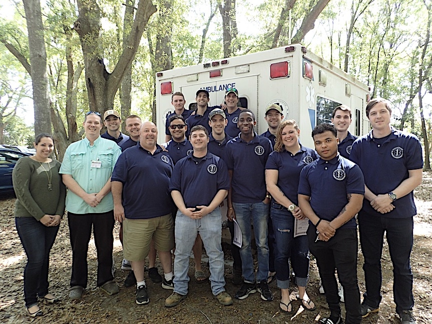 A group of people posing in front of an ambulance.