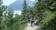 A man walking down a trail with a backpack.