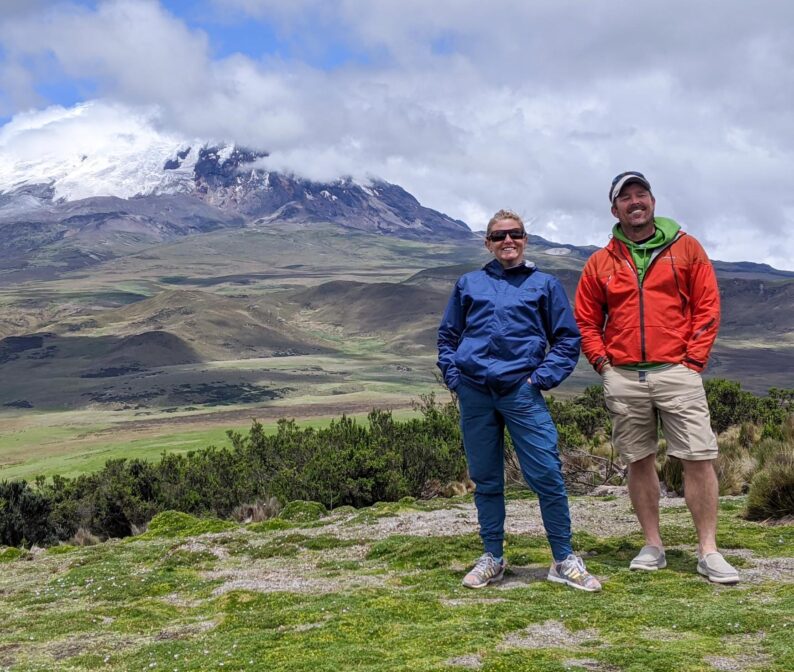 Two people smiling with a view of a mountain in the background.