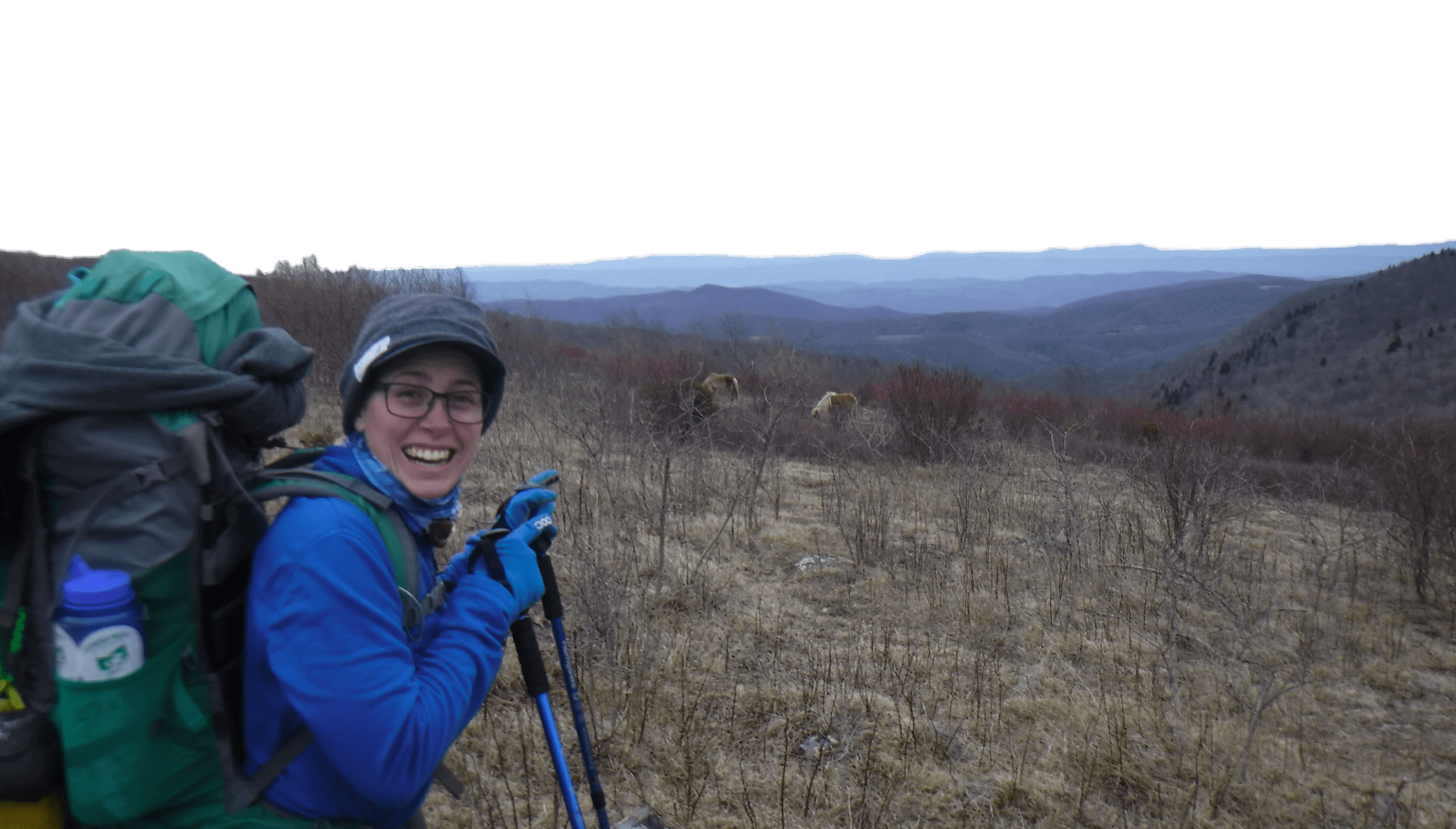 A person wearing backpacking and hiking gear smiling.