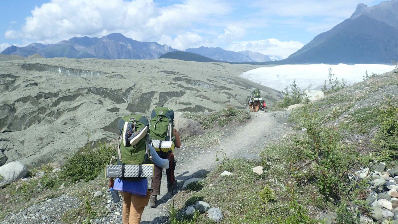 People backpacking on a trail in Alaska.