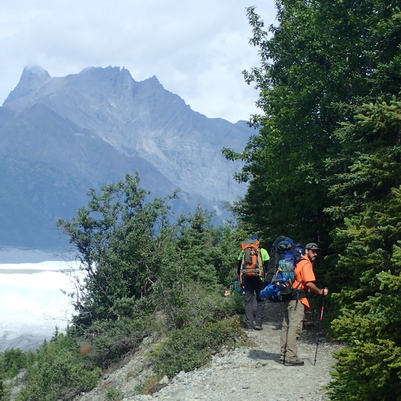 People on a hiking trail alongside a mountain view.