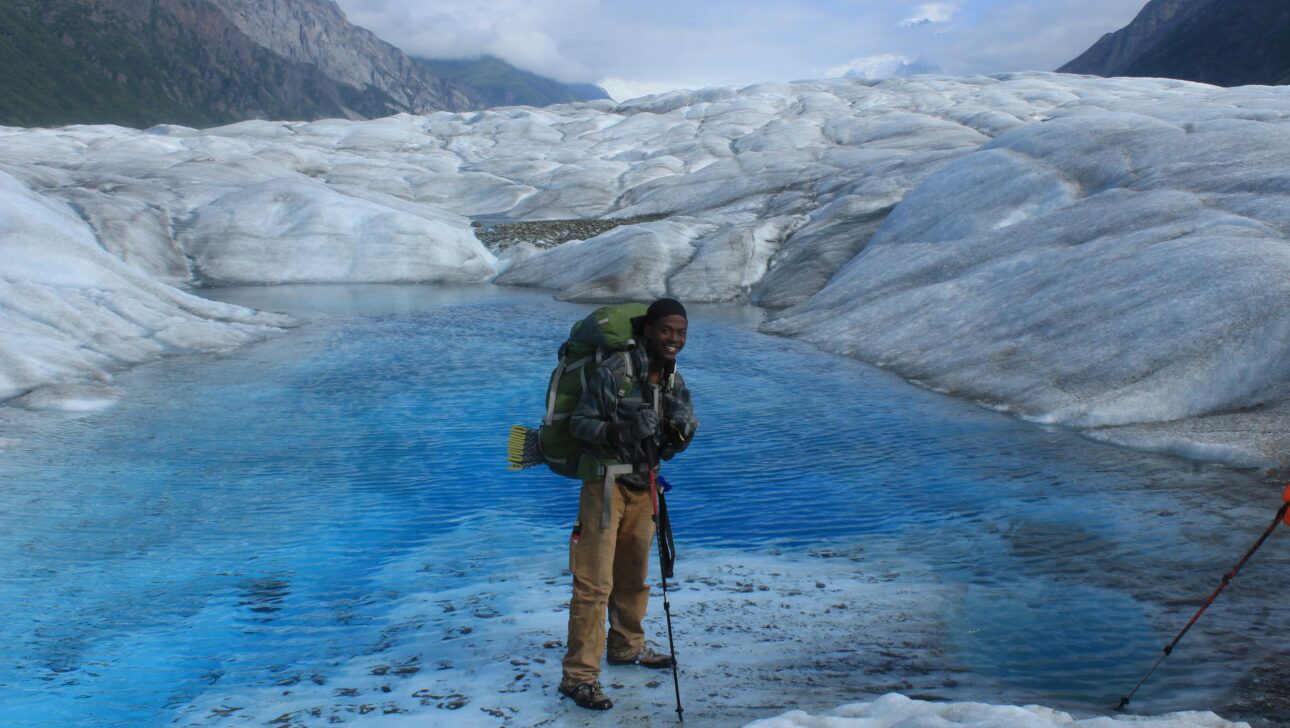 A person standing by a ice and a body of water in Alaska.