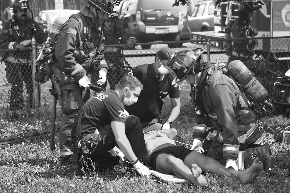 A black and white photo of a man being treated by a firefighter.