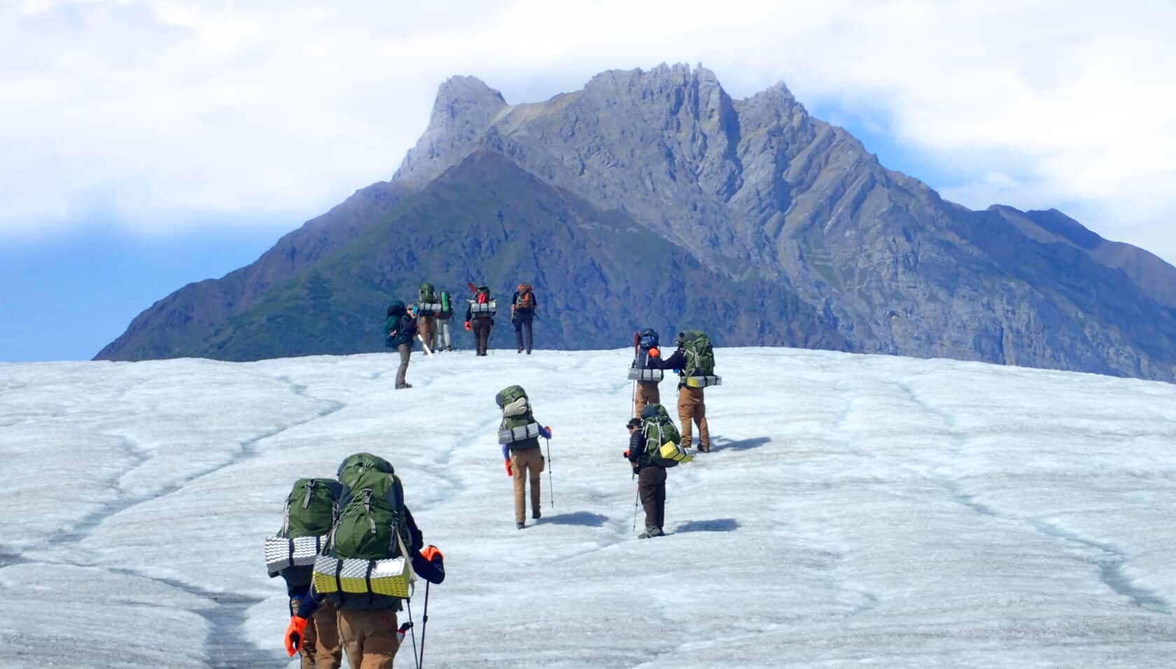 A group of people backpacking up a mountain in Alaska.