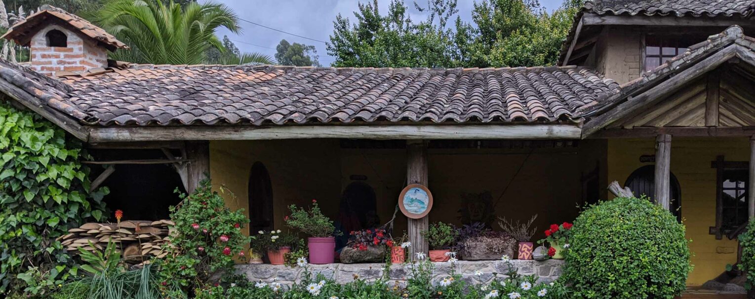 The outside of a house in Ecuador, decorated with potted plants.