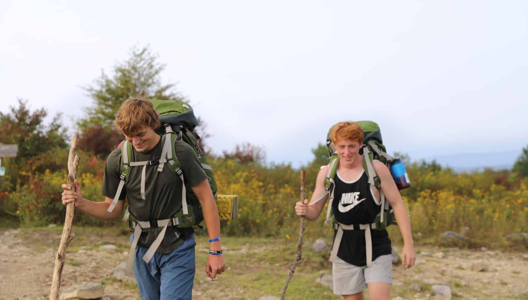 Two students hiking with backpacking gear.