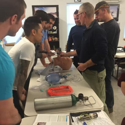 A group of EMT instructors at a table learning a procedure.