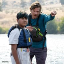 A field instructor pointing forward alongside a student standing in water.