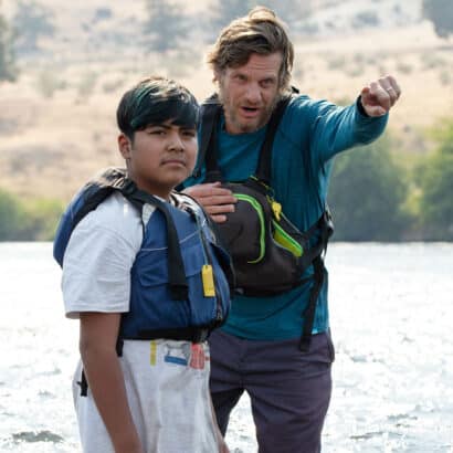 A field instructor pointing forward alongside a student standing in water.