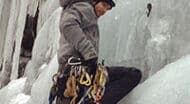 A man climbing up an icy waterfall.