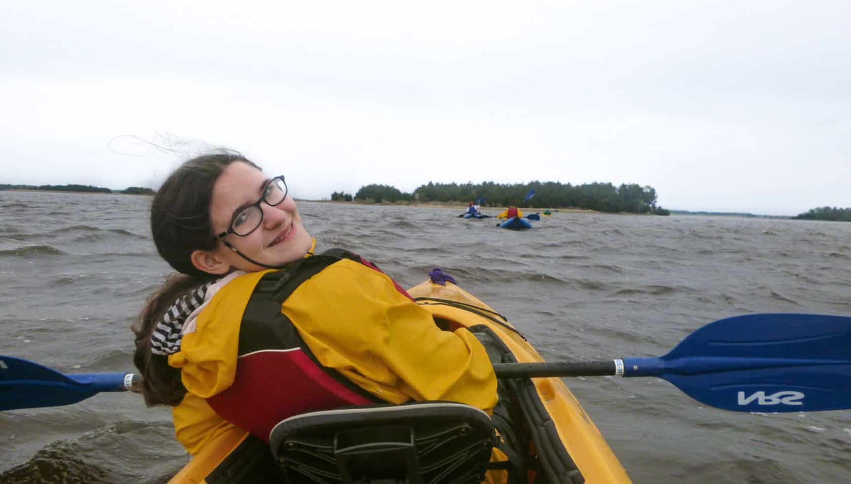 A girl on a kayaking looking back and smiling.