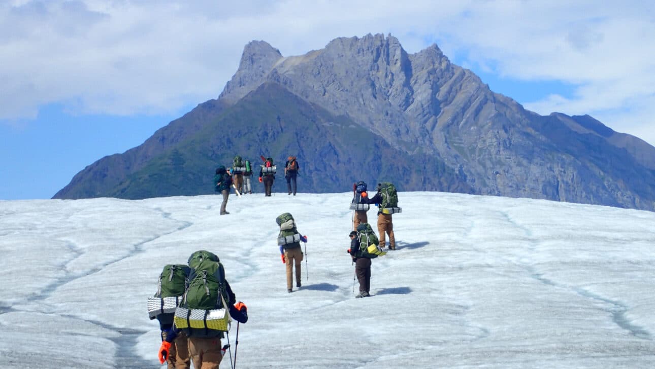 A group of people backpacking up a mountain in Alaska.