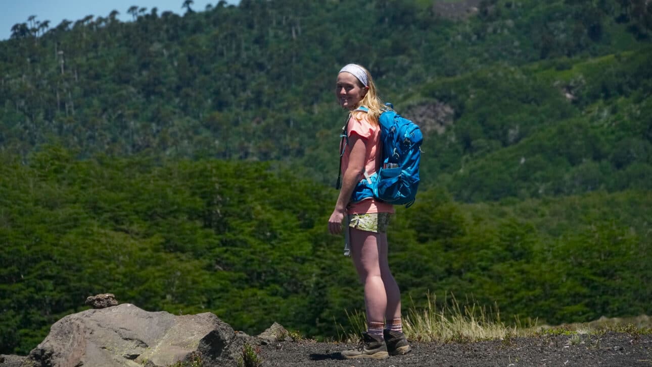 A woman with hiking gear, smiling.