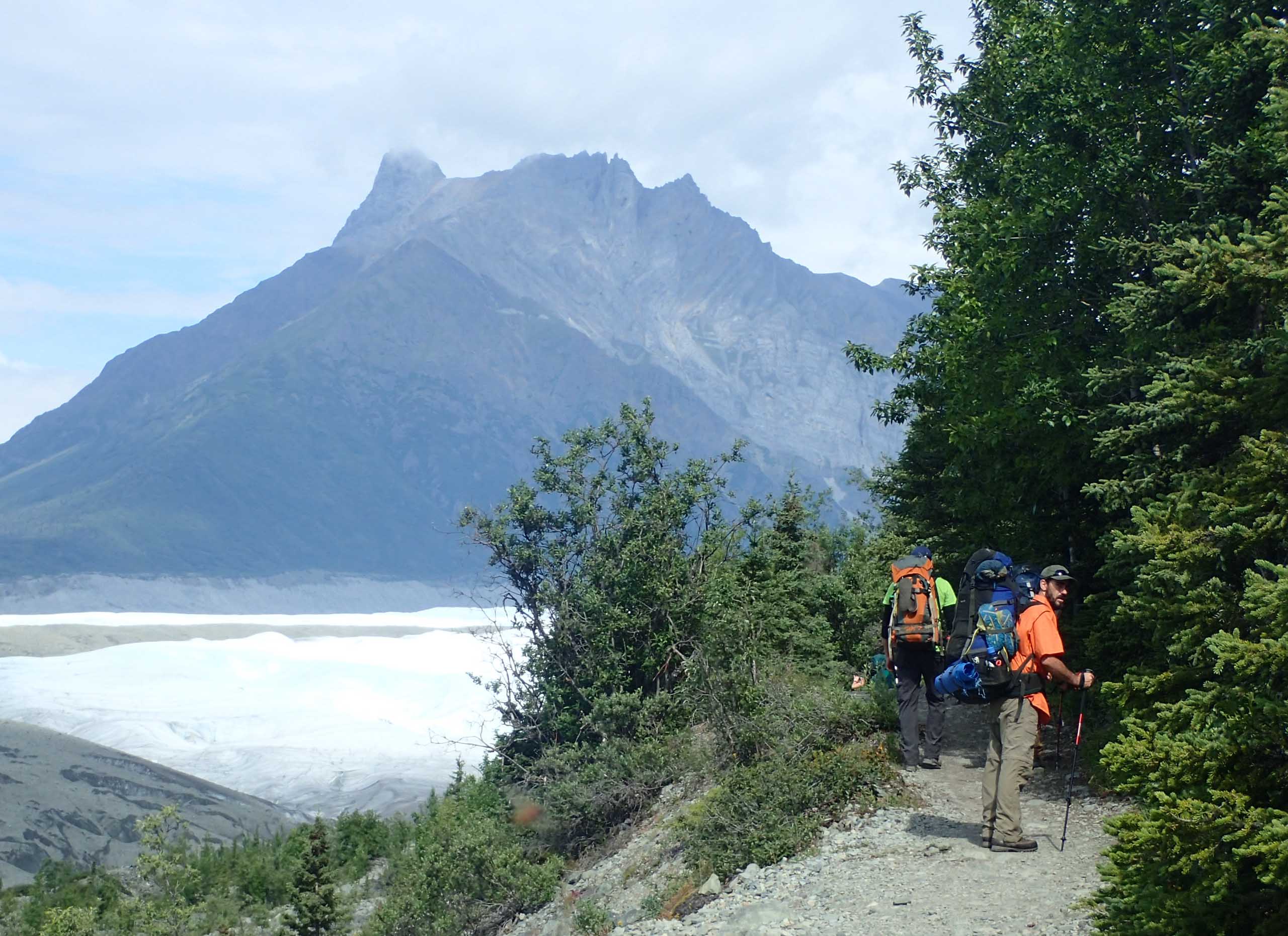 People on a hiking trail alongside a mountain view.