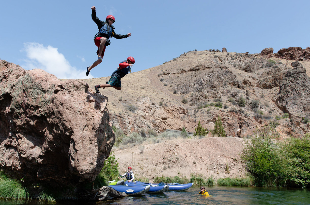 Two people jumping into a lake.