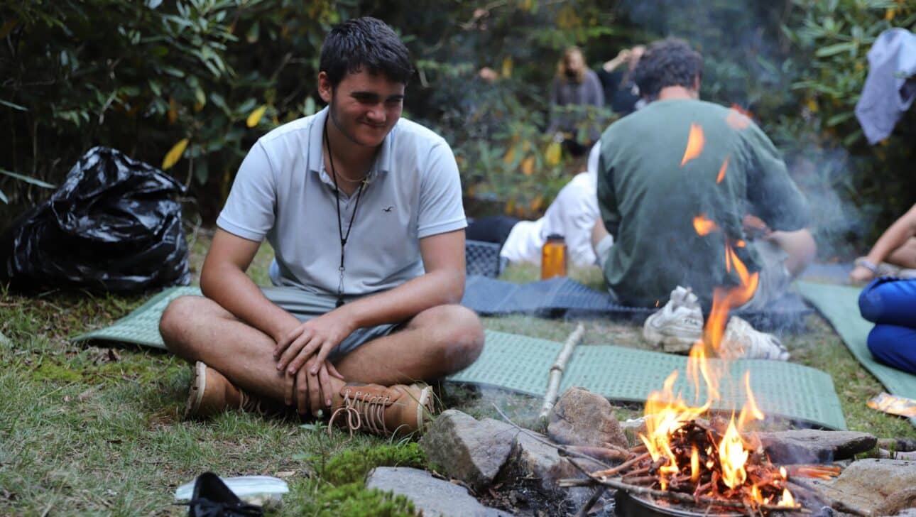 A man sitting next to a firepit.