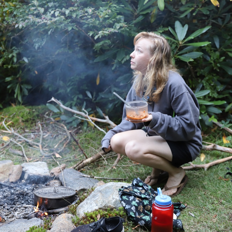 A woman cooking a meal over a fire.