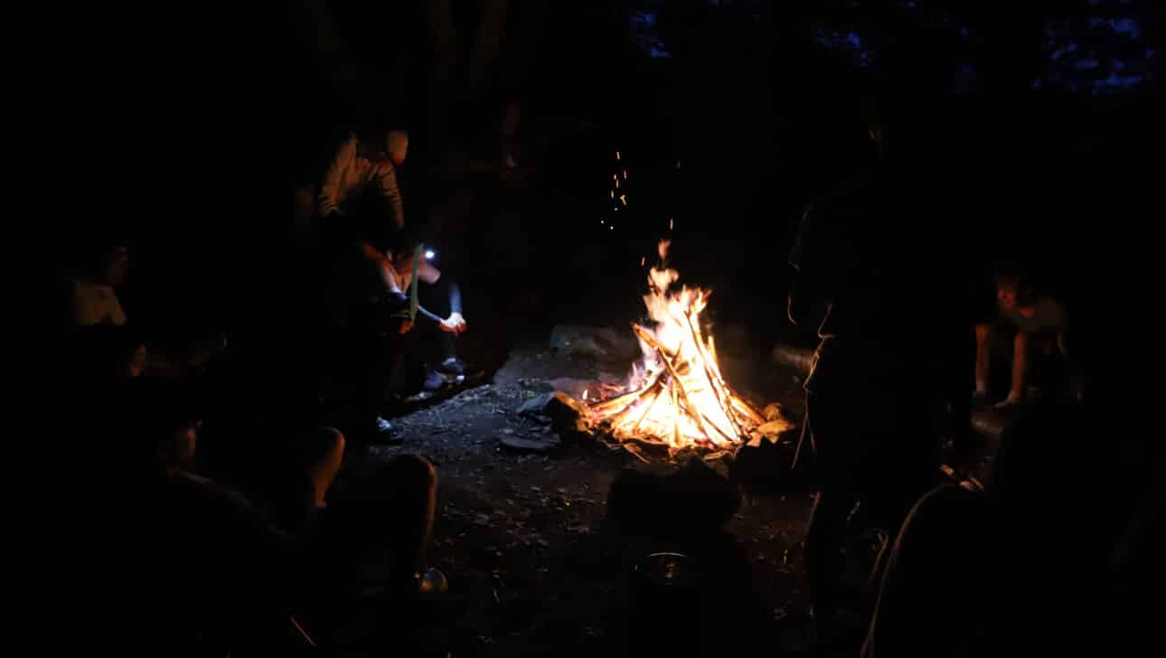 People gathered around a camp fire at night.