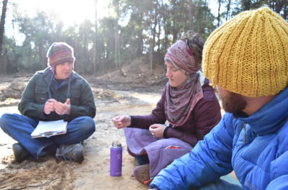 Three outdoor educators sitting on the ground together.