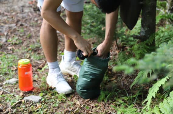 A person packing clothing into a small bag.