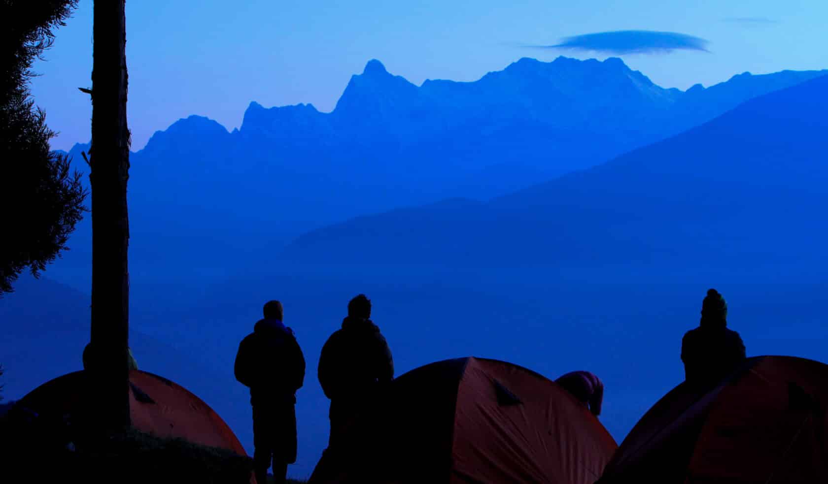 People admiring a view of mountains at dawn.