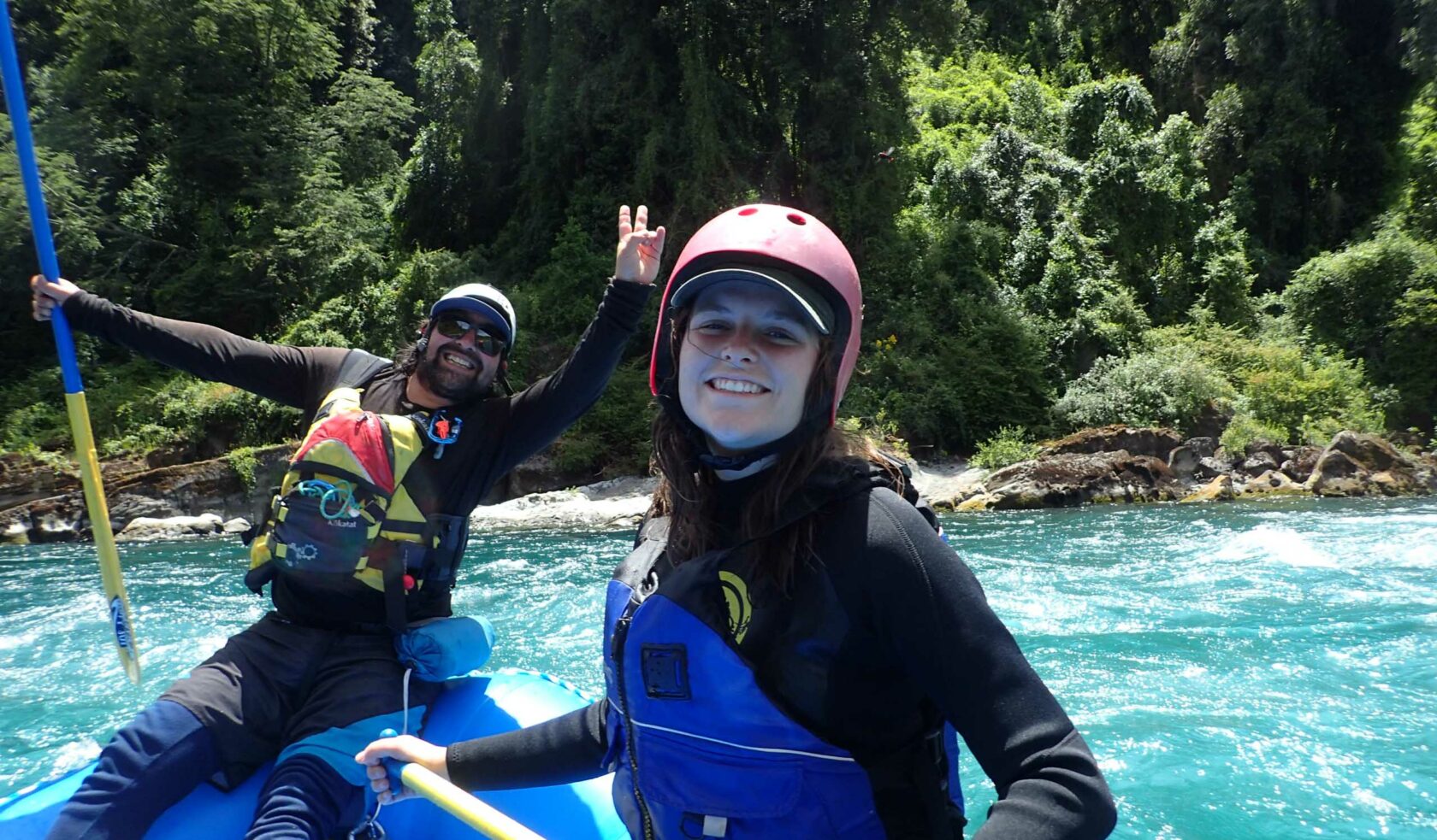 Two people smiling on a whitewater raft.