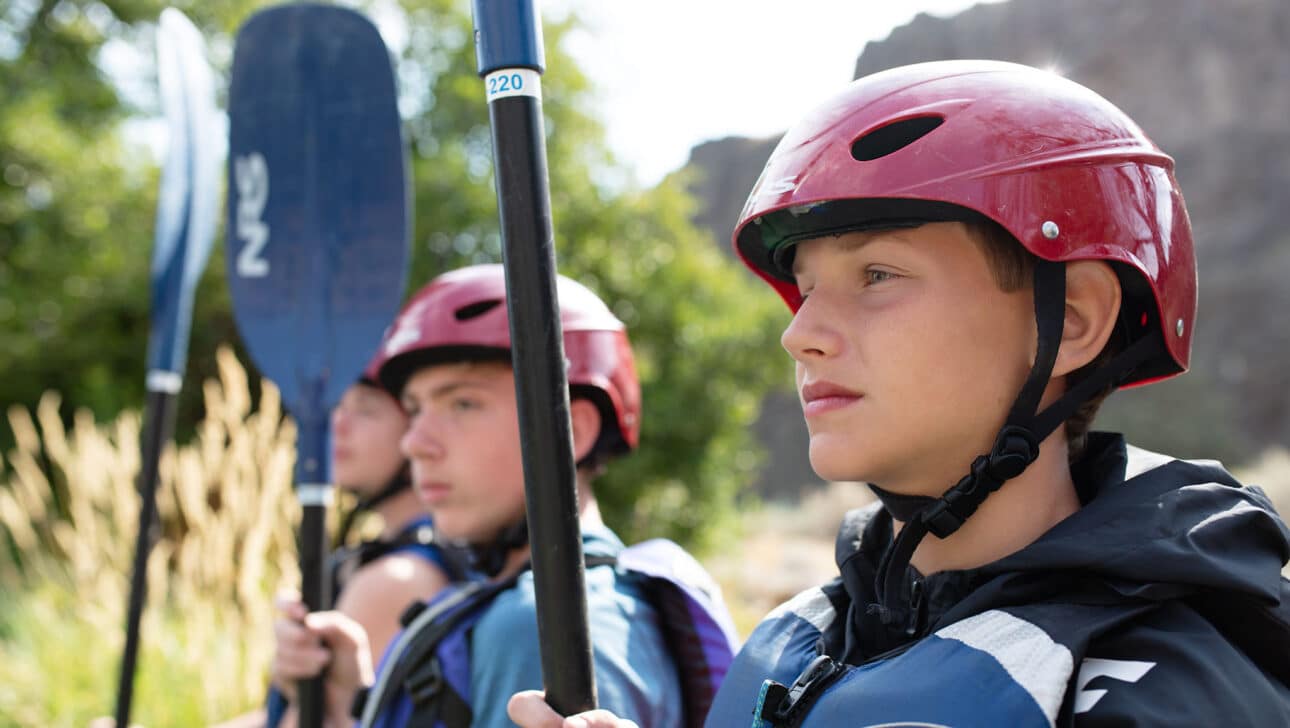 A close up of two boys in whitewater paddling gear.