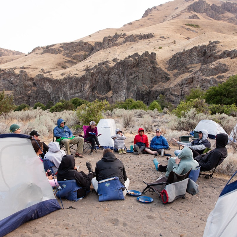 A group of people sitting in a circle with tents around them.
