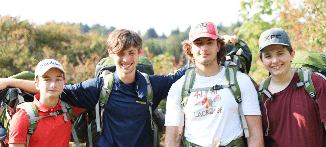 Four smiling students wearing backpacking gear.