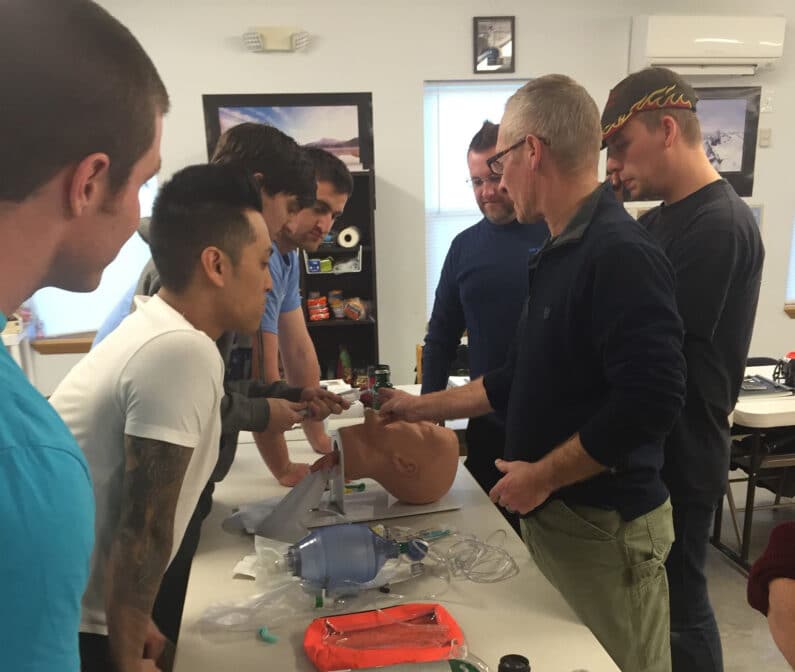 A group of EMT instructors at a table learning a procedure.