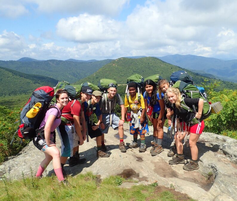 A group of teenagers at the top of a mountain.