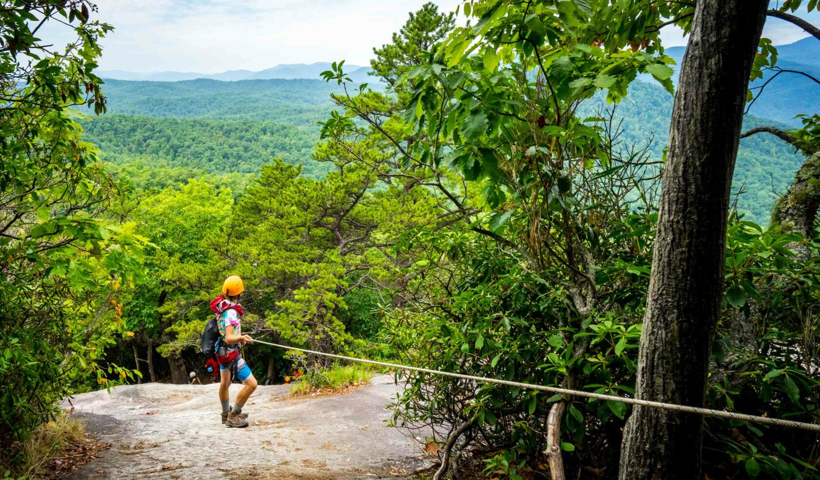 A student rock climbing and holding onto a handline.