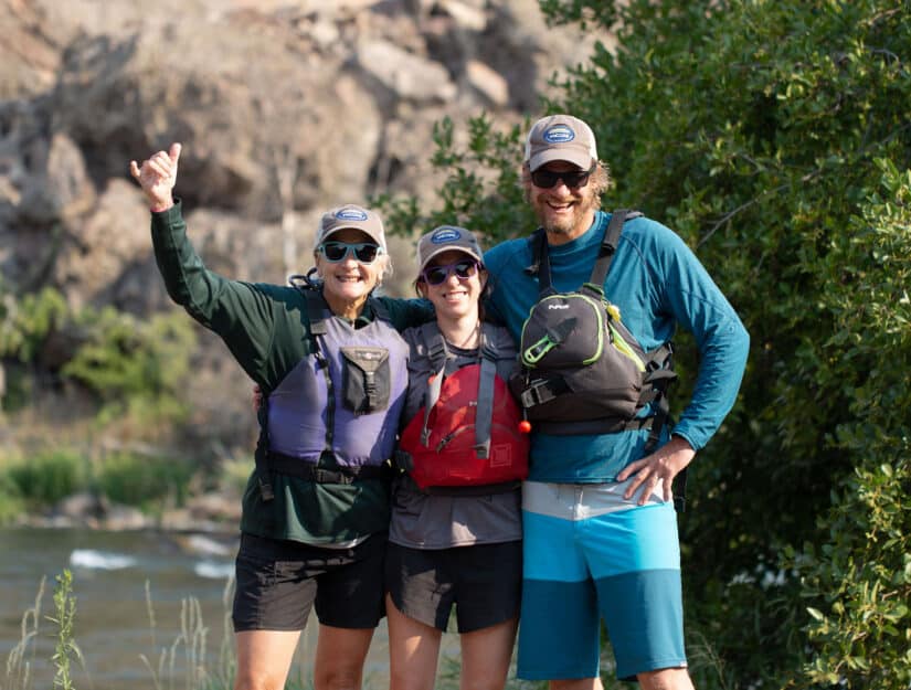 Three adults in hiking gear, smiling.