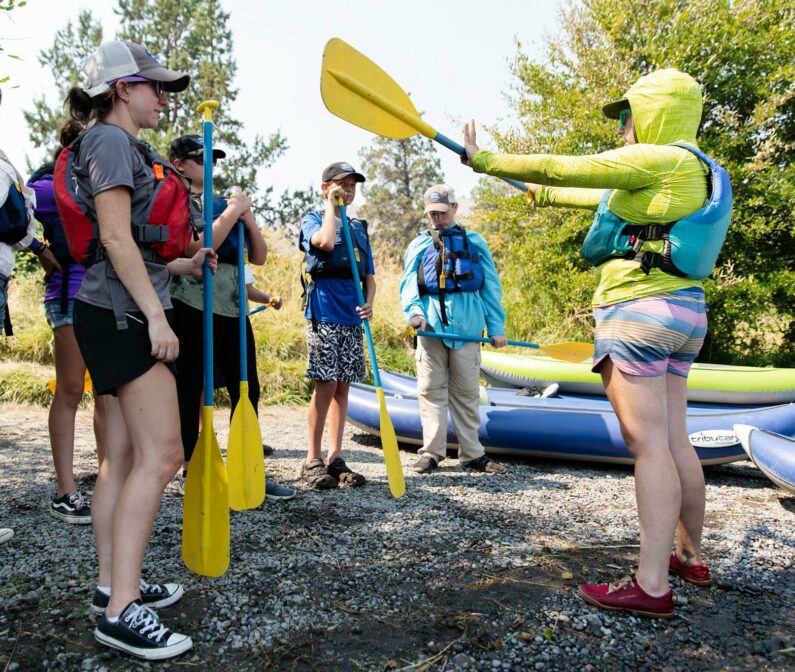 An NCOAE field instructor showing students how to use a paddle.