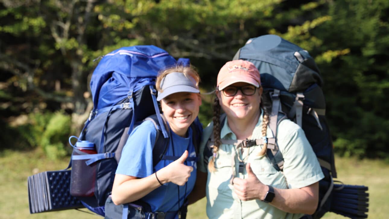 Two women with backpacking gear, smiling.