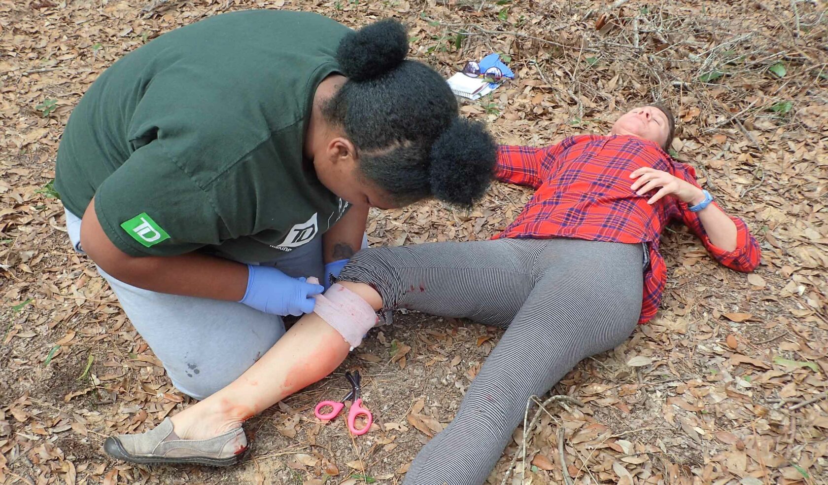 A wilderness medicine personnel wrapping a bandage around a patient's leg.