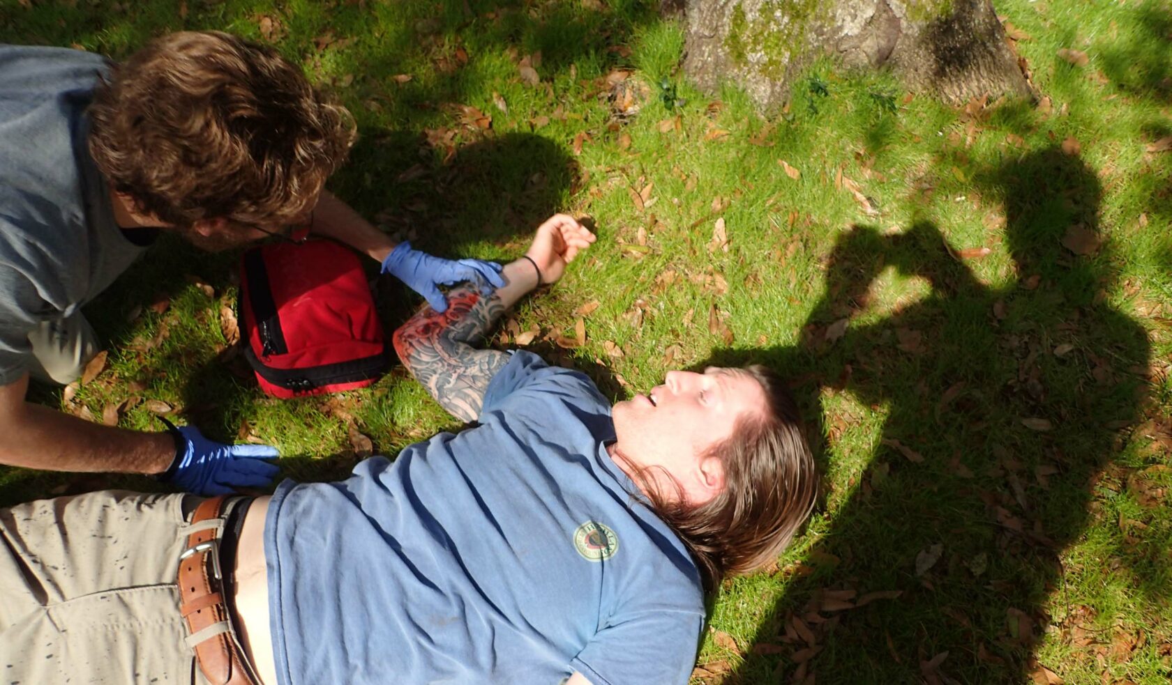 A wilderness medicine personnel examining a patient in a field.