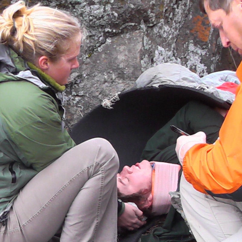 Two wilderness medicine personnel helping a patient.