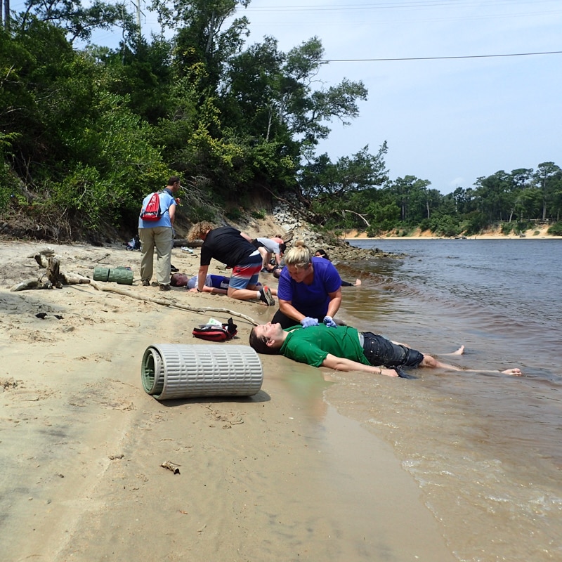 Wilderness medicine personnel treating several patients on a lake shore.
