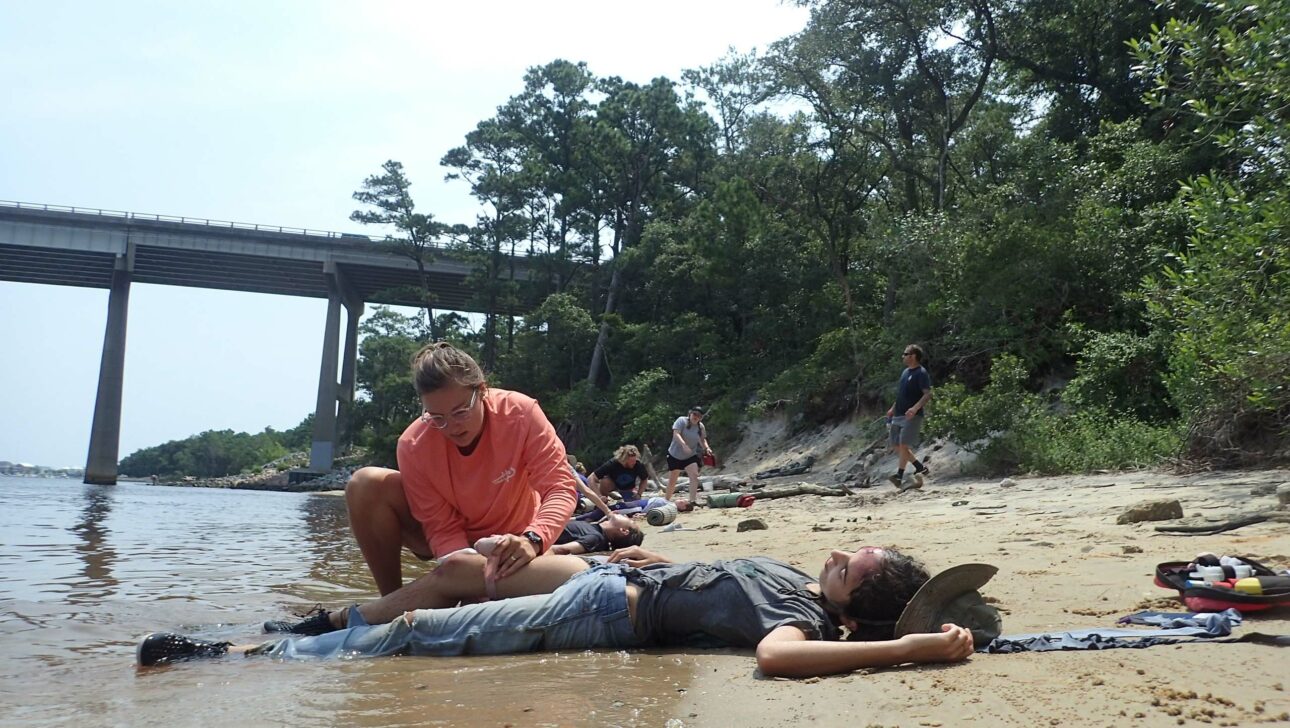 Wilderness medicine students treating injuries on a lake shore.