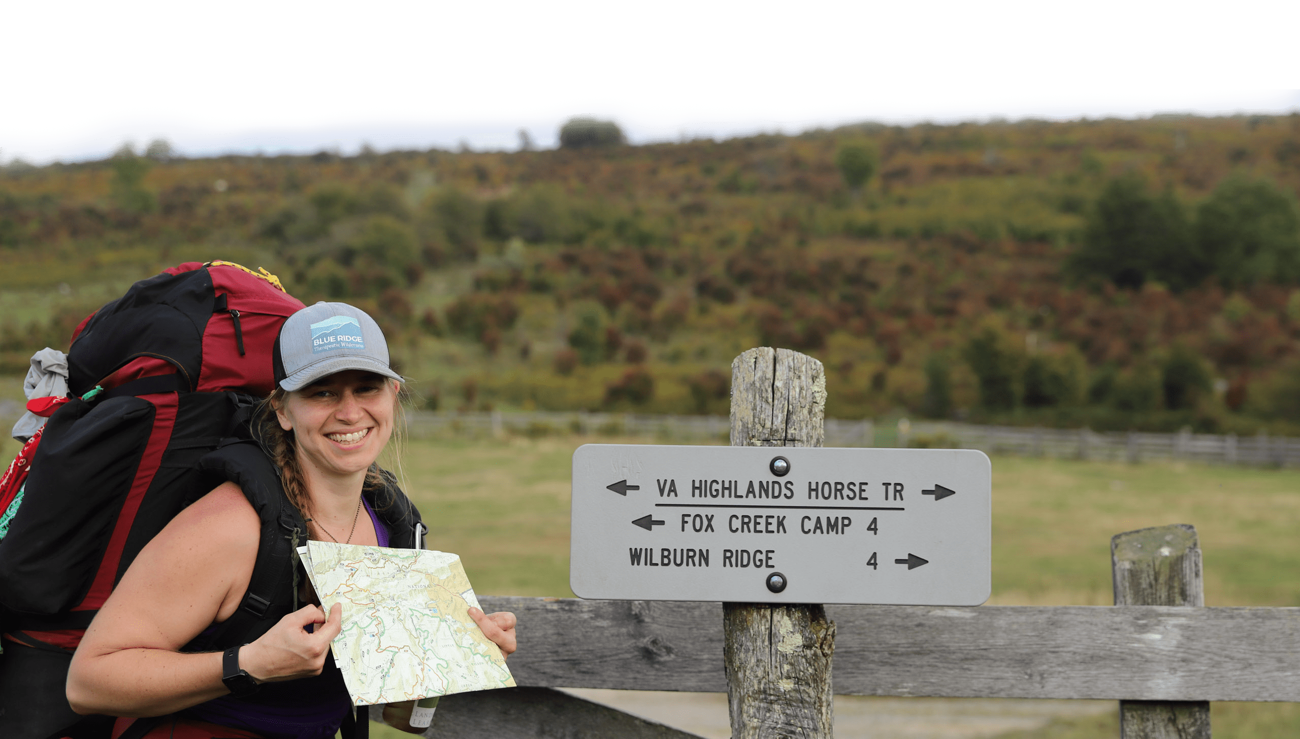 A woman with backpacking gear, holding a map.