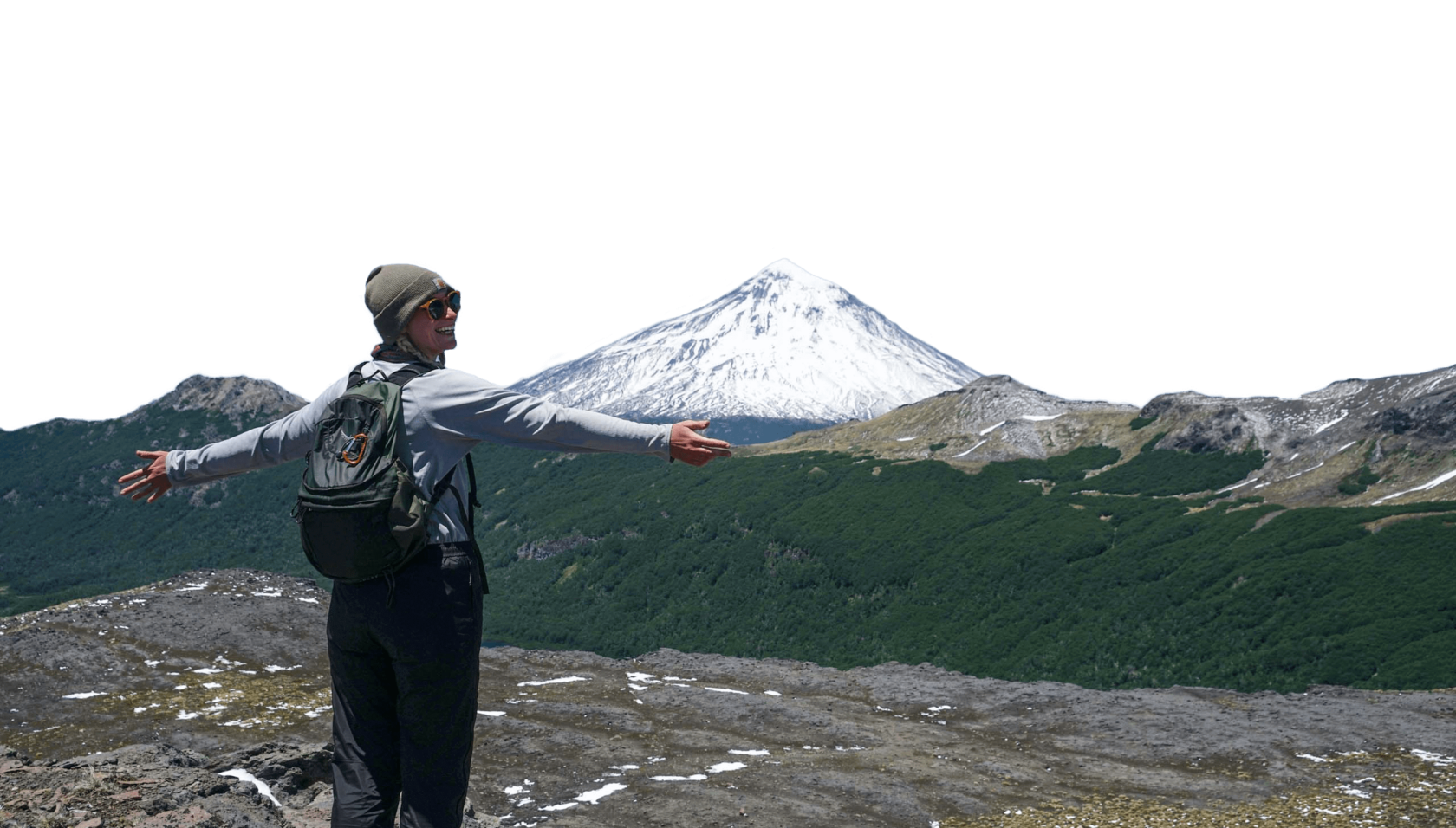 A woman with her arms outstretched towards a view of a snowcapped mountain.