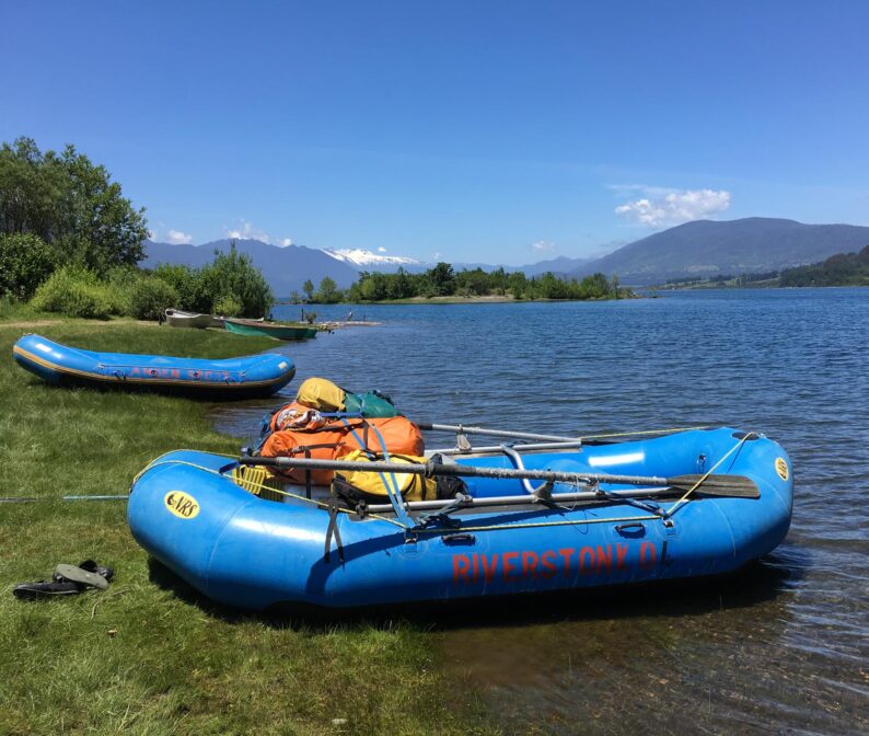 Two blue whitewater rafts on a shore.